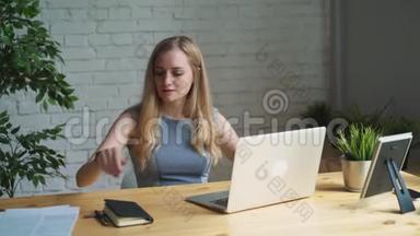 一位有创意的女士坐在办公桌前的肖像。 使用笔记本。 她坐在轻盈现代的办公室里